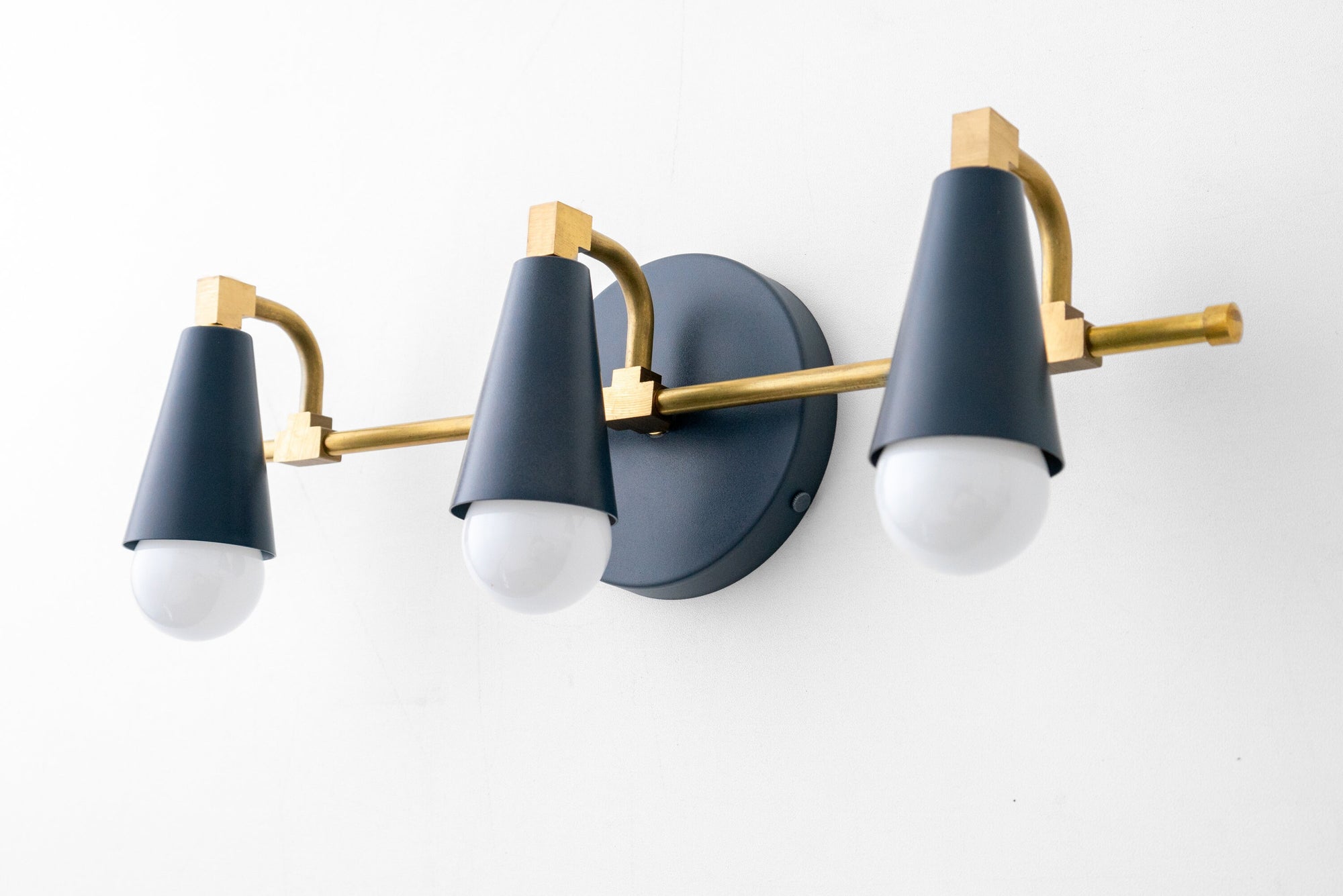 Three-bulb vanity light with matte coal blue shades and raw brass accents on a wall mount. - VANITY LIGHT MODEL NO. 8084