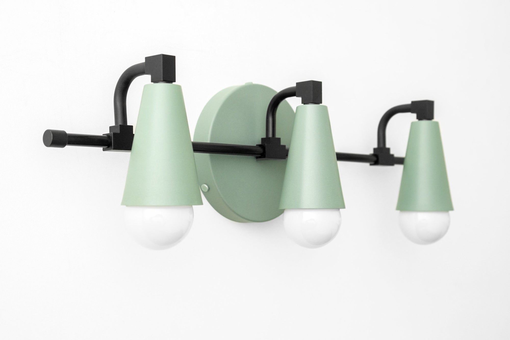 Three-bulb vanity light with matte sage green conical shades and black metal mounting on white wall. - VANITY LIGHT MODEL NO. 8084