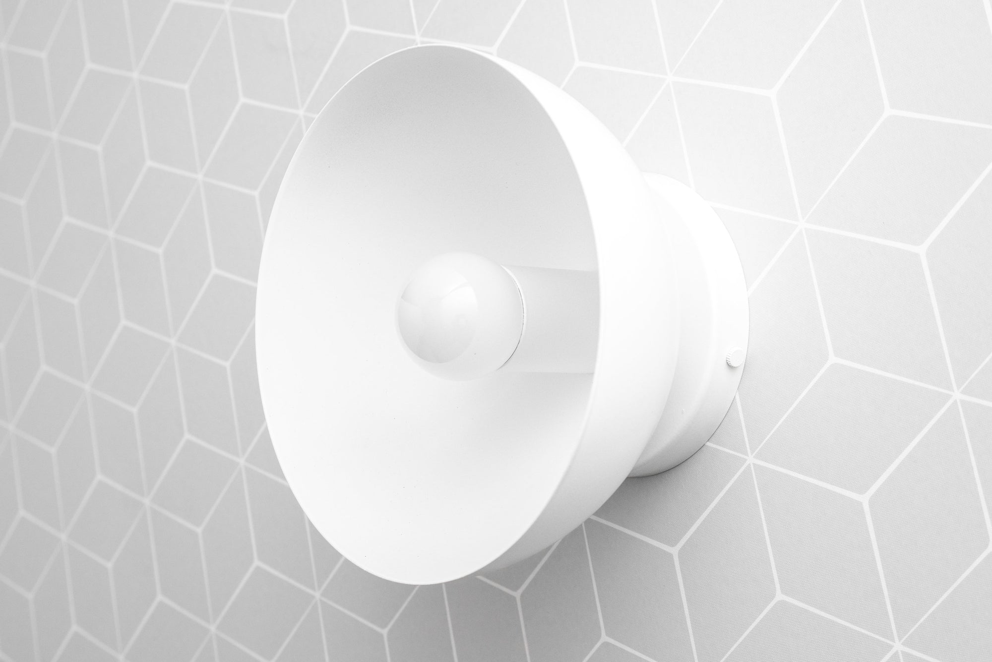 White matte dome-shaped wall sconce with exposed bulb on geometric tiled wall. - SCONCE MODEL NO. 9105