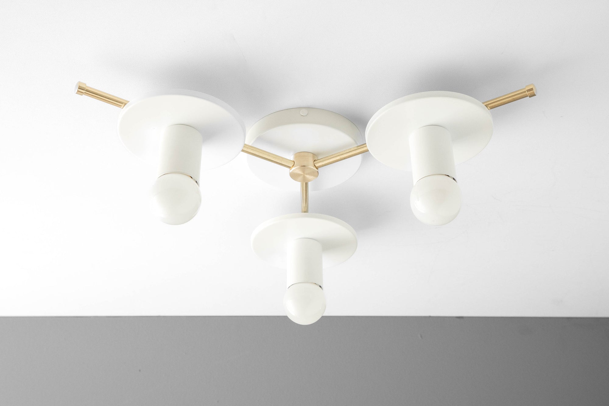 Flush mount chandelier with three matte white cylindrical shades and raw brass arms. - CHANDELIER MODEL NO. 9526