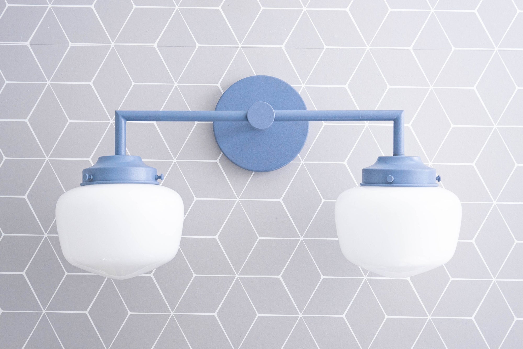 Art Deco style vanity light with two white globe bulbs and matte coal blue metal frame against geometric tile wall background. - VANITY LIGHT MODEL NO. 0276