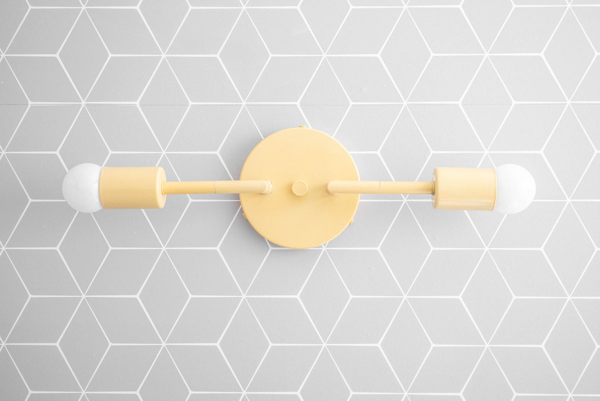 Matte yellow mid-century modern vanity light with two exposed bulbs on geometric gray tile background. - VANITY LIGHT MODEL NO. 1938