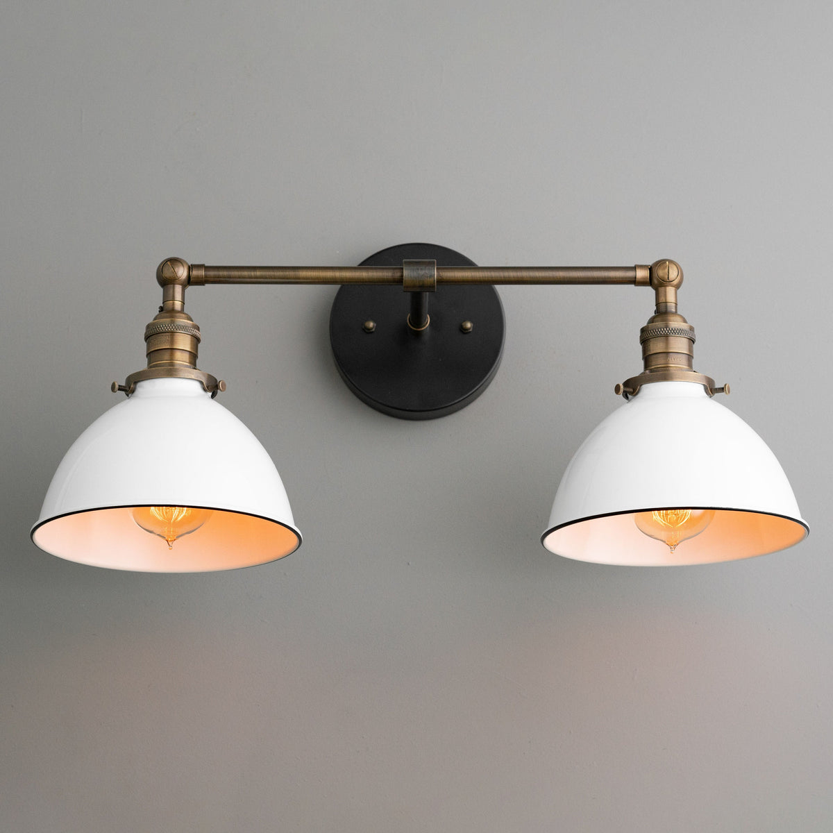 Industrial-style two-bulb vanity light with white metal shades and antique brass finish on wall mount. - VANITY LIGHT MODEL NO. 4564