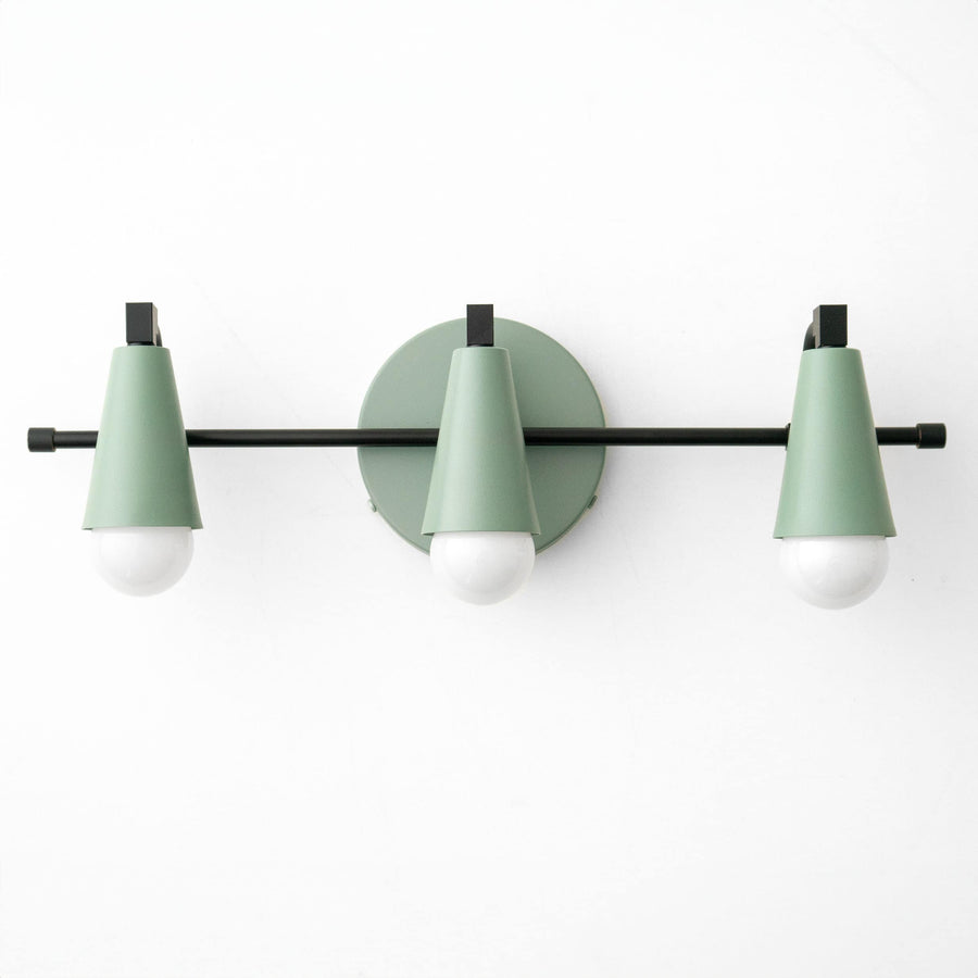 Three-bulb vanity light with matte black bar and muted green conical shades against white wall. - VANITY LIGHT MODEL NO. 8084