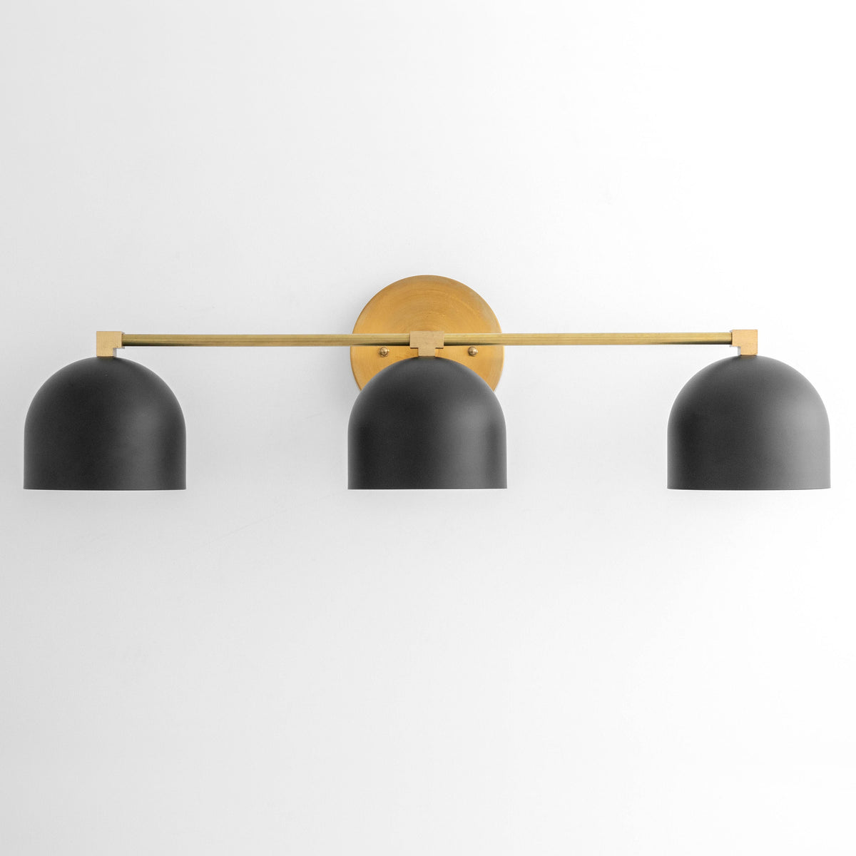 Mid-century modern vanity light with three black dome shades and antique brass horizontal bar. - VANITY LIGHT MODEL NO. 7565