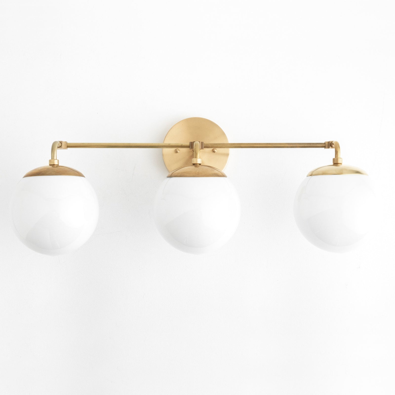 Mid-century modern vanity light with three white glass globes and raw brass finish. - VANITY LIGHT MODEL NO. 9319