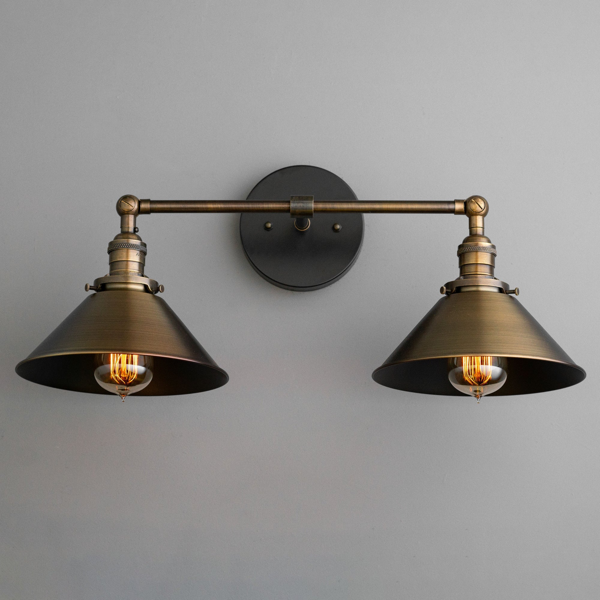 Two-bulb industrial vanity light with antique brass conical shades and round black wall mount. - VANITY LIGHT MODEL NO. 1861