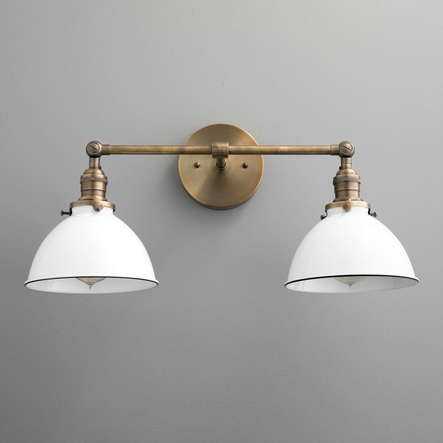 Two-bulb vanity light with antique brass finish and white industrial-style shades against gray wall. - VANITY LIGHT MODEL NO. 4564
