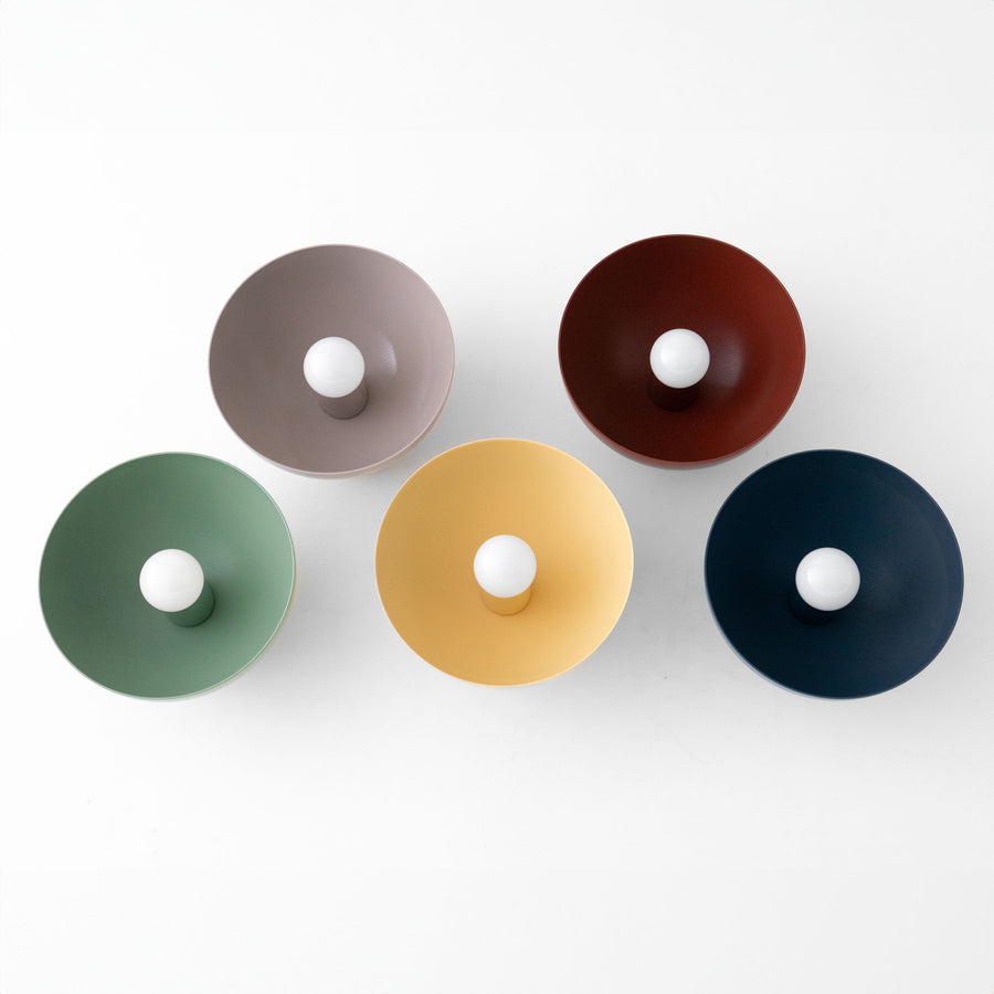 Five dome-shaped wall sconces in mauve, brick red, green, yellow, and coal blue with exposed bulbs arranged on a white. - SCONCE MODEL NO. 9105