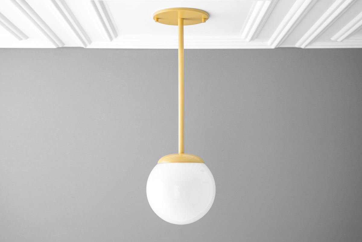 Mid-century modern pendant light with matte yellow ceiling mount and frosted white globe shade. - PENDANT MODEL NO. 7559