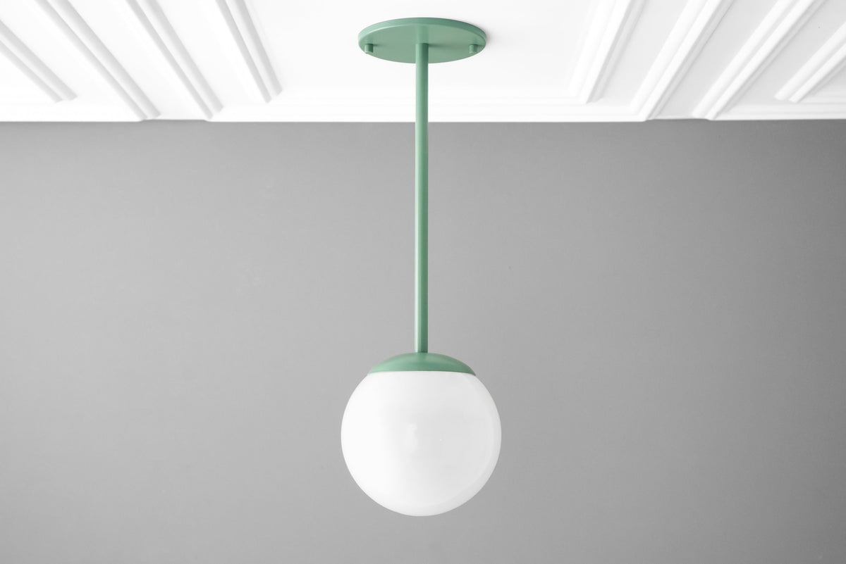 Matte green mid-century modern pendant light with a white globe shade hanging from ceiling mount. - PENDANT MODEL NO. 7559