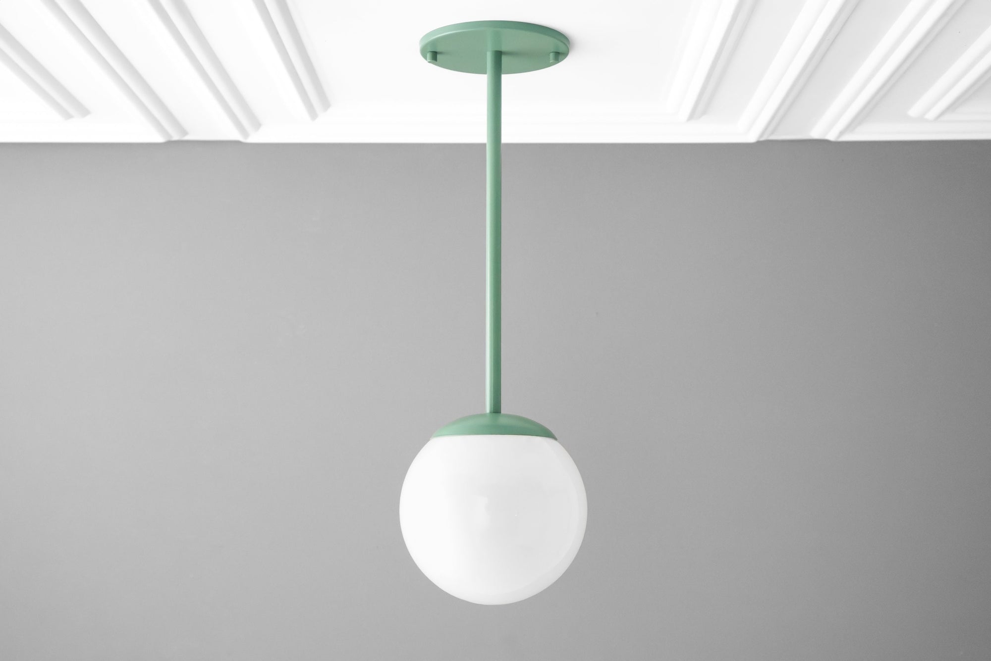 Matte green mid-century modern pendant light with a white globe shade hanging from ceiling mount. - PENDANT MODEL NO. 7559