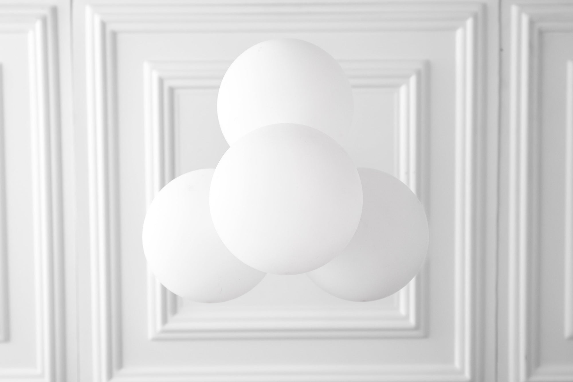 Modern chandelier with three white frosted glass globes mounted on a white ceiling with decorative molding. - CHANDELIER MODEL NO. 9834