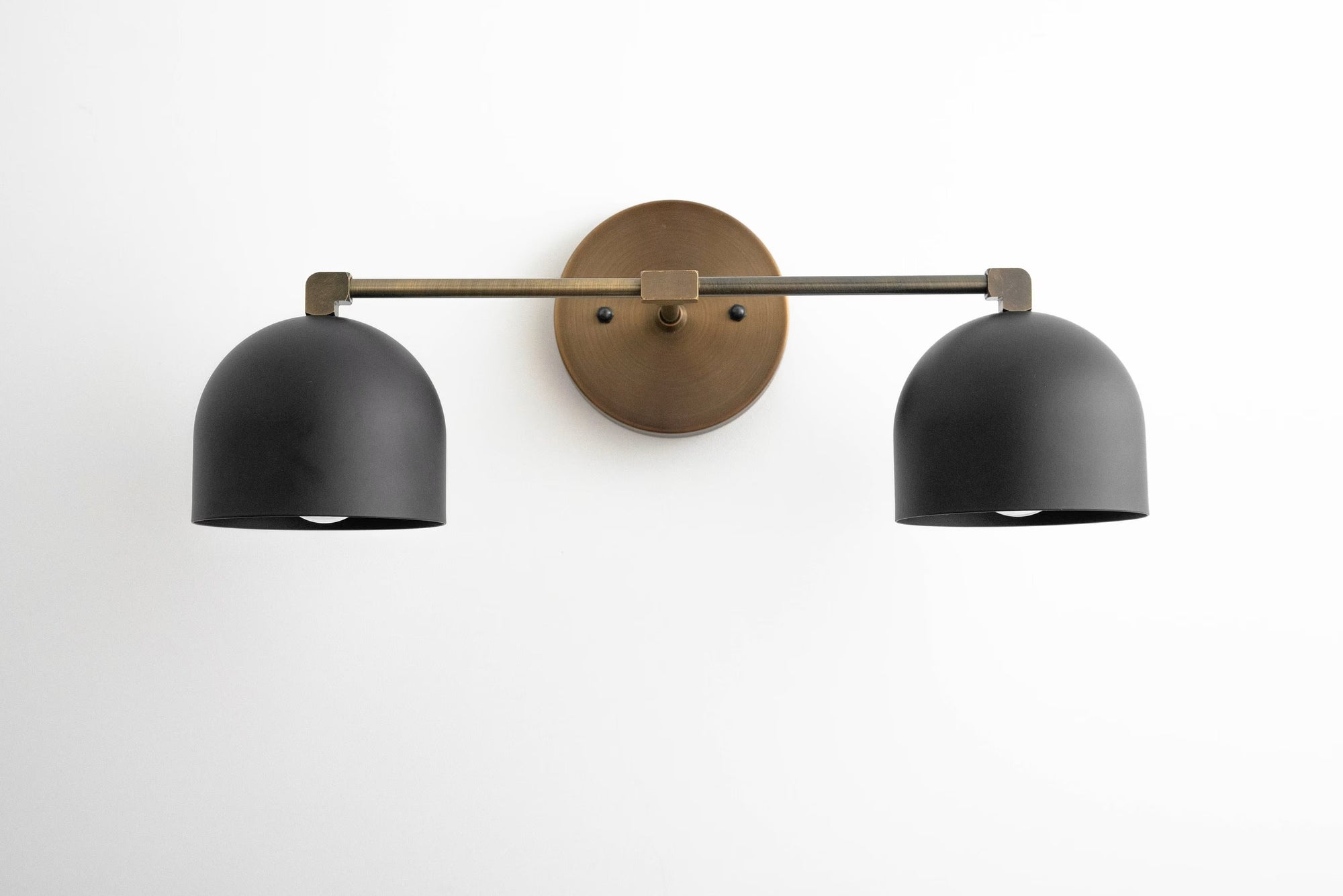 Mid-century modern two-bulb vanity light with matte black dome shades and antique brass mounting plate. - VANITY LIGHT MODEL NO. 0698