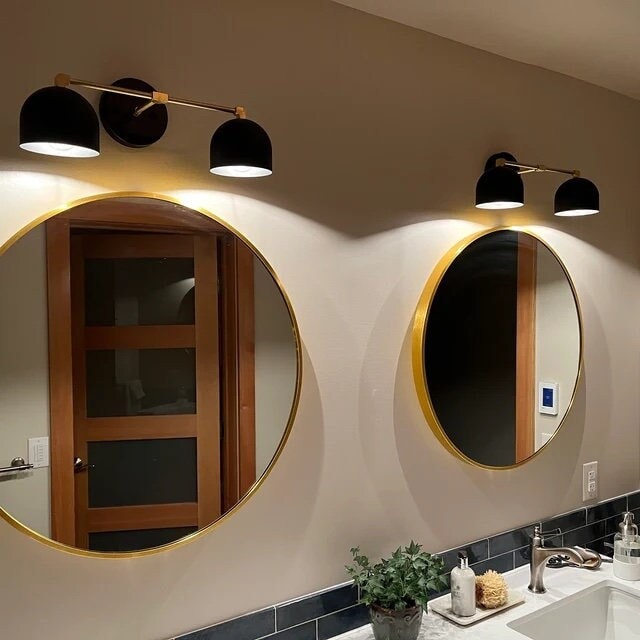 Two-bulb mid-century modern black vanity light above round gold-framed mirrors in bathroom. - VANITY LIGHT MODEL NO. 0698