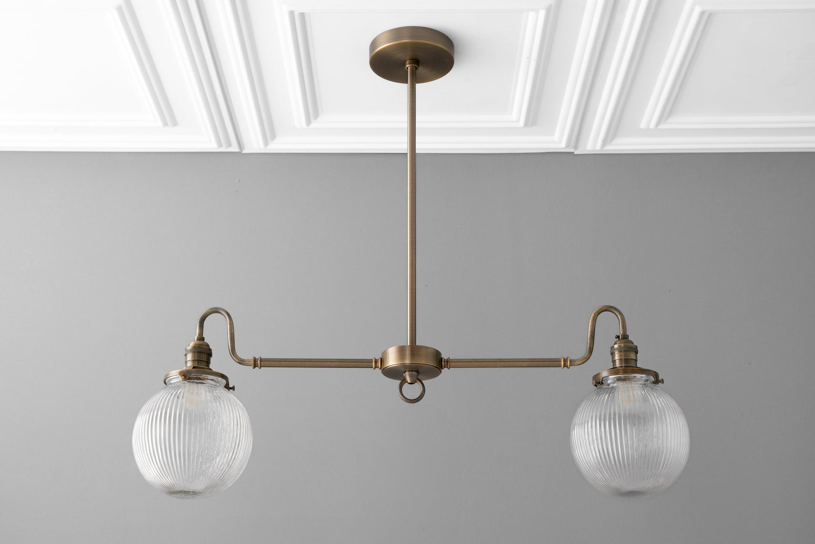 Antique brass linear chandelier with two clear globe glass shades and textured pattern. - CHANDELIER MODEL NO. 7424