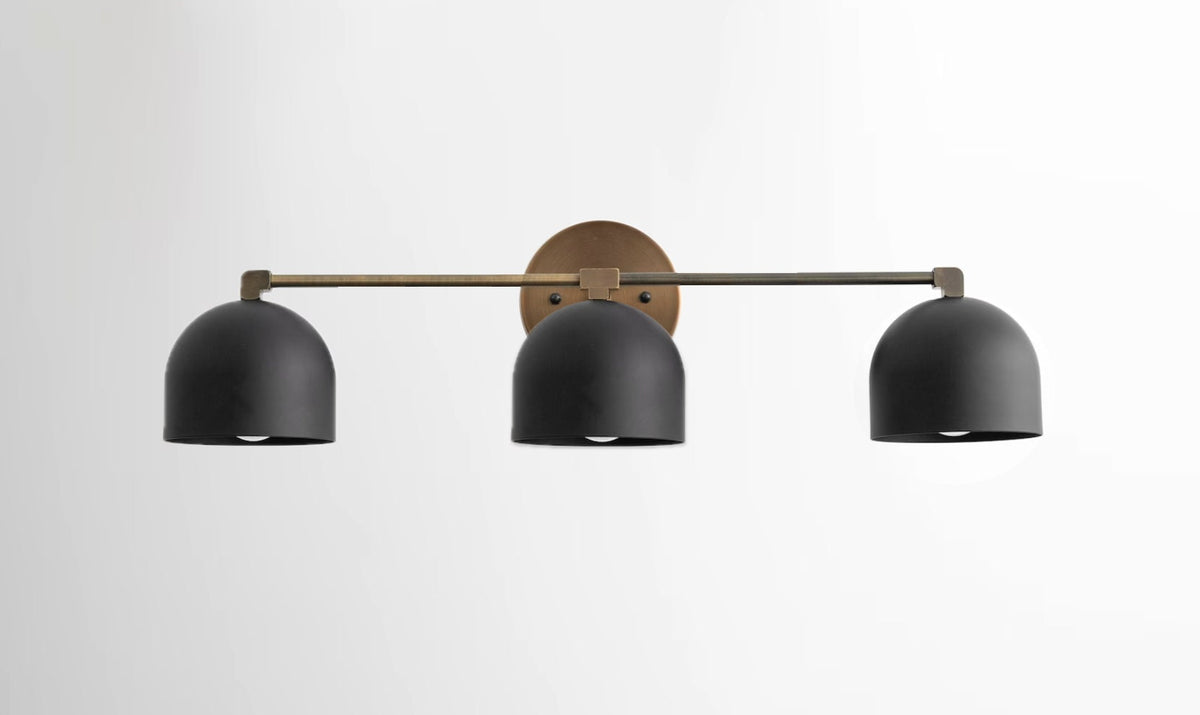 Mid-century modern 3-bulb vanity light with matte black dome shades and antique brass mounting plate. - VANITY LIGHT MODEL NO. 7565
