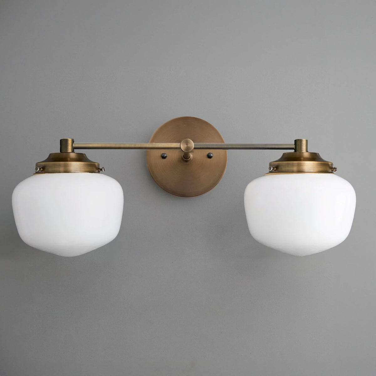 Mid-century modern two-bulb vanity light with round frosted glass globes and antique brass fixtures. - VANITY LIGHT MODEL NO. 5799