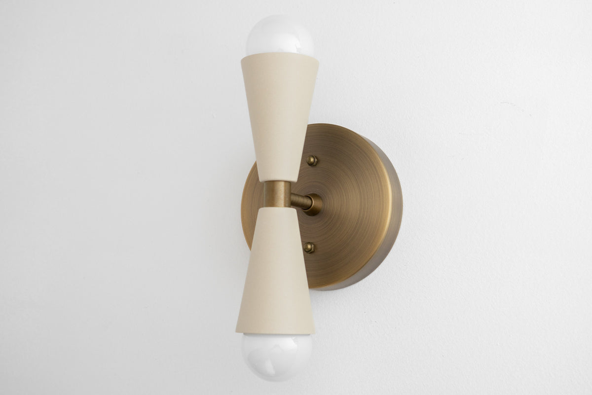Antique brass wall sconce with cream double cone-shaped holders and exposed bulbs up and down. - SCONCE MODEL NO. 4717