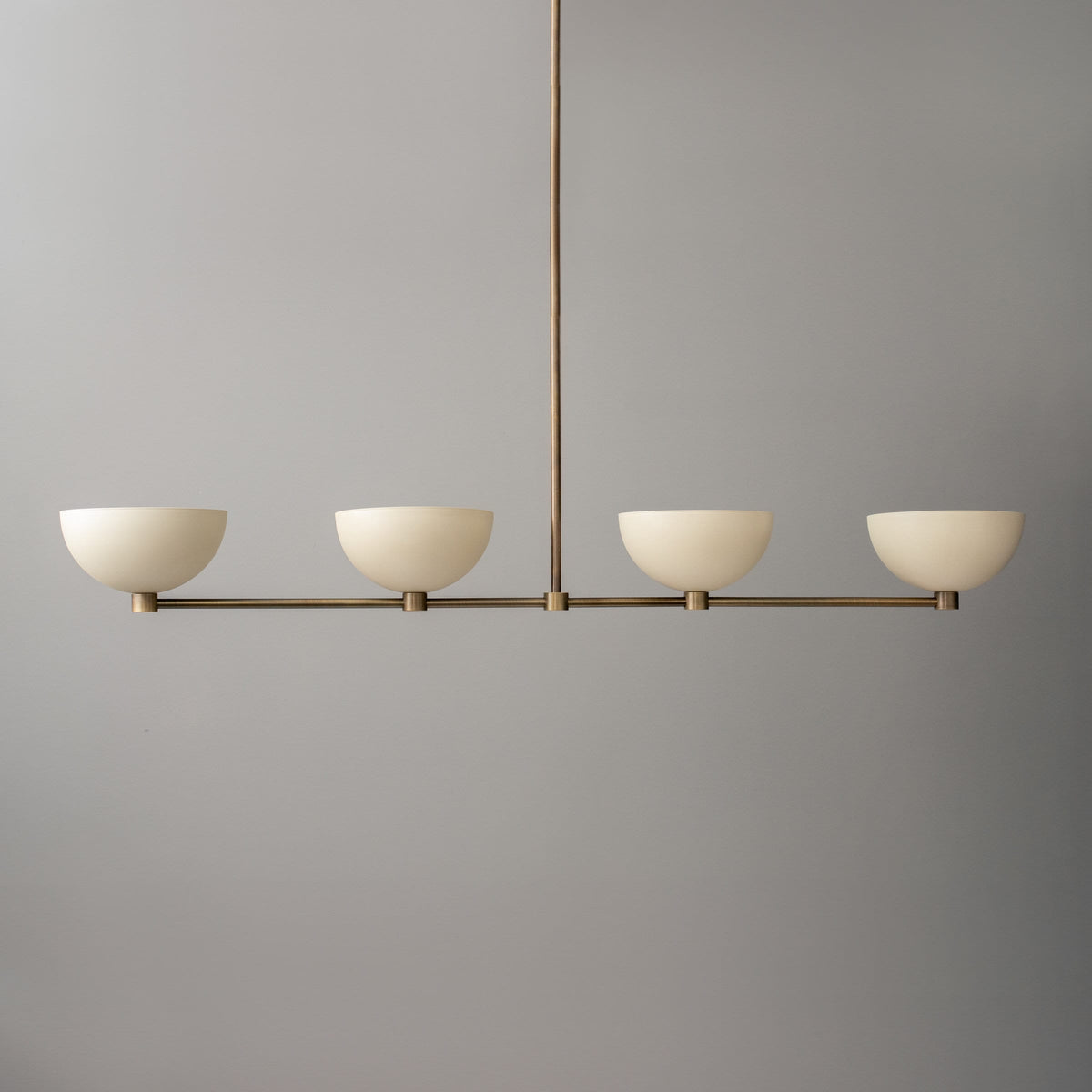 Linear chandelier with four cream dome shades and antique brass finish hanging fixture. - CHANDELIER MODEL NO. 4577