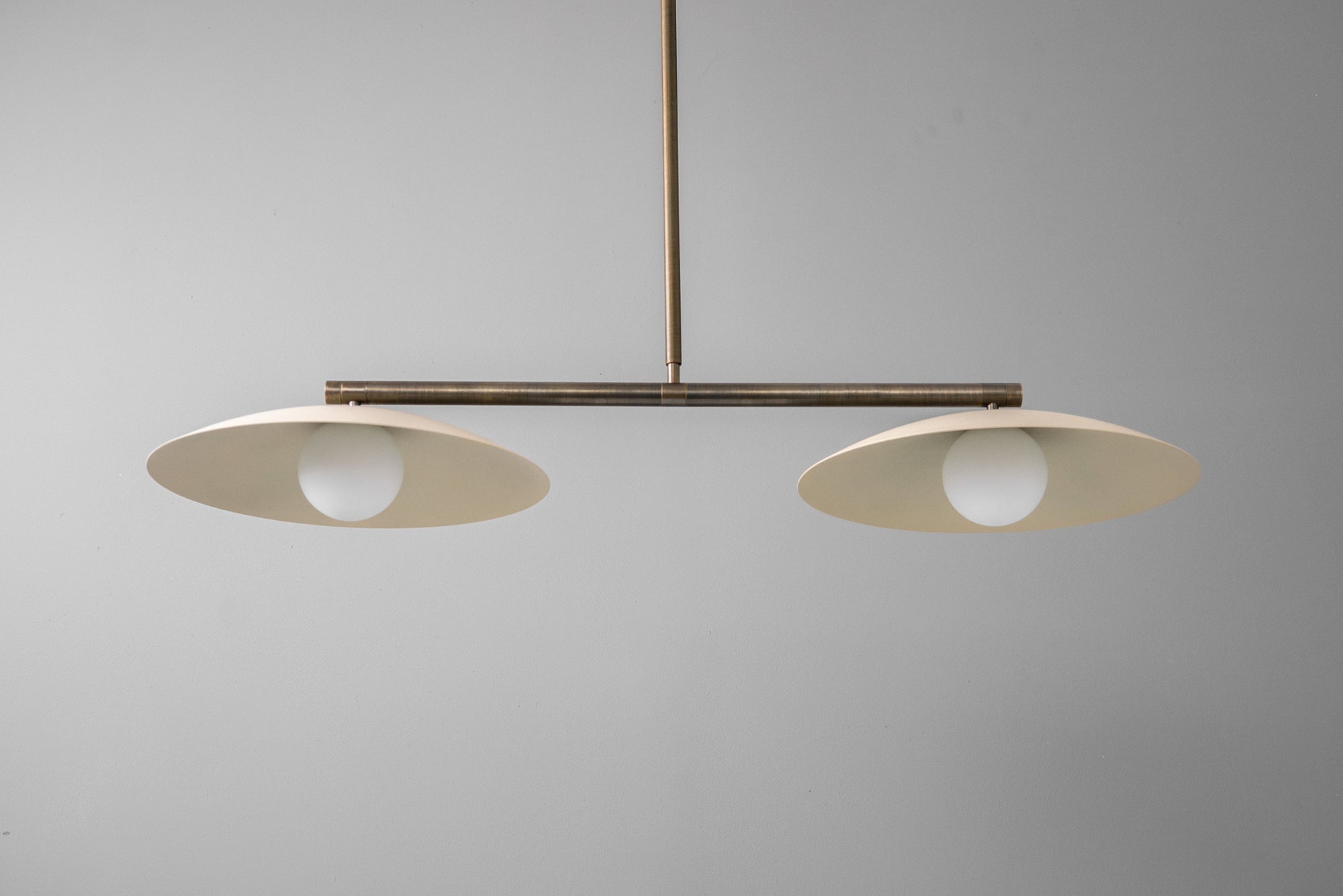 Minimalist linear chandelier with two flat antique brass globe shades and exposed bulbs. - CHANDELIER MODEL NO. 9708