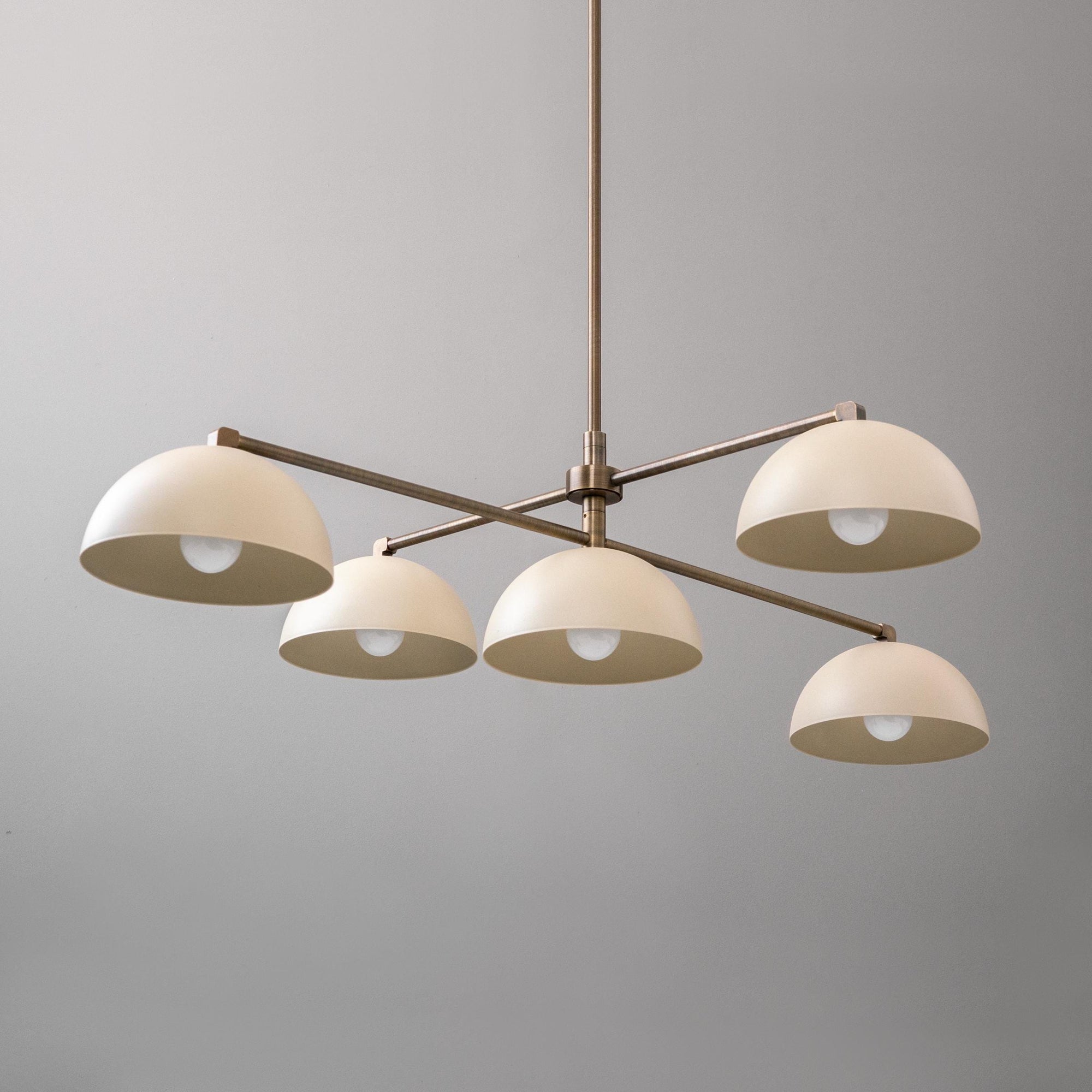 Mid-century modern chandelier with five white dome shades and an antique brass frame suspended from ceiling. - CHANDELIER MODEL NO. 7041