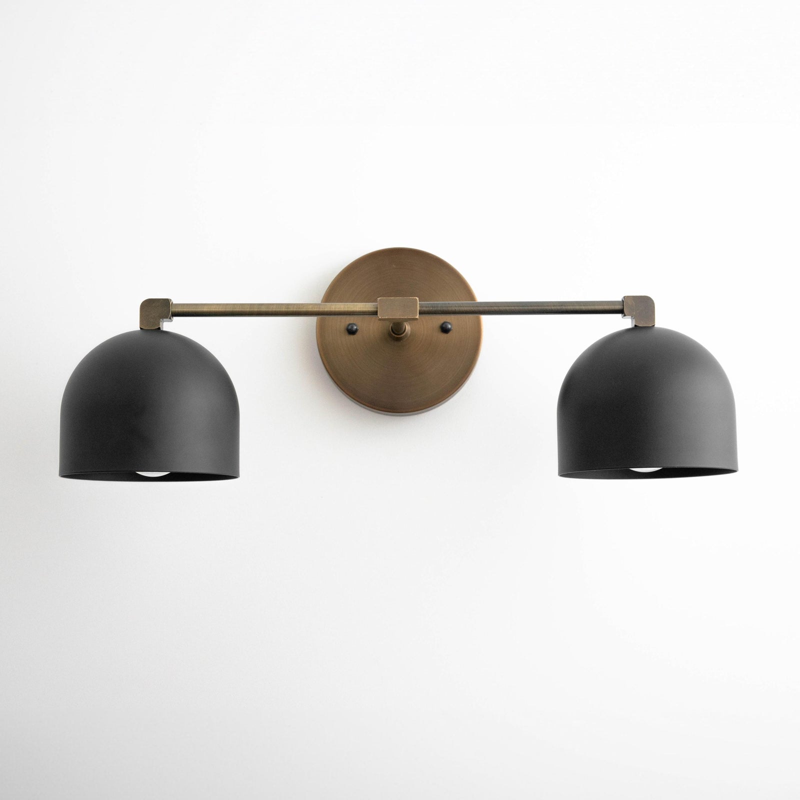 Mid-century modern two-bulb vanity light with matte black dome shades and antique brass wall mount. - VANITY LIGHT MODEL NO. 0698