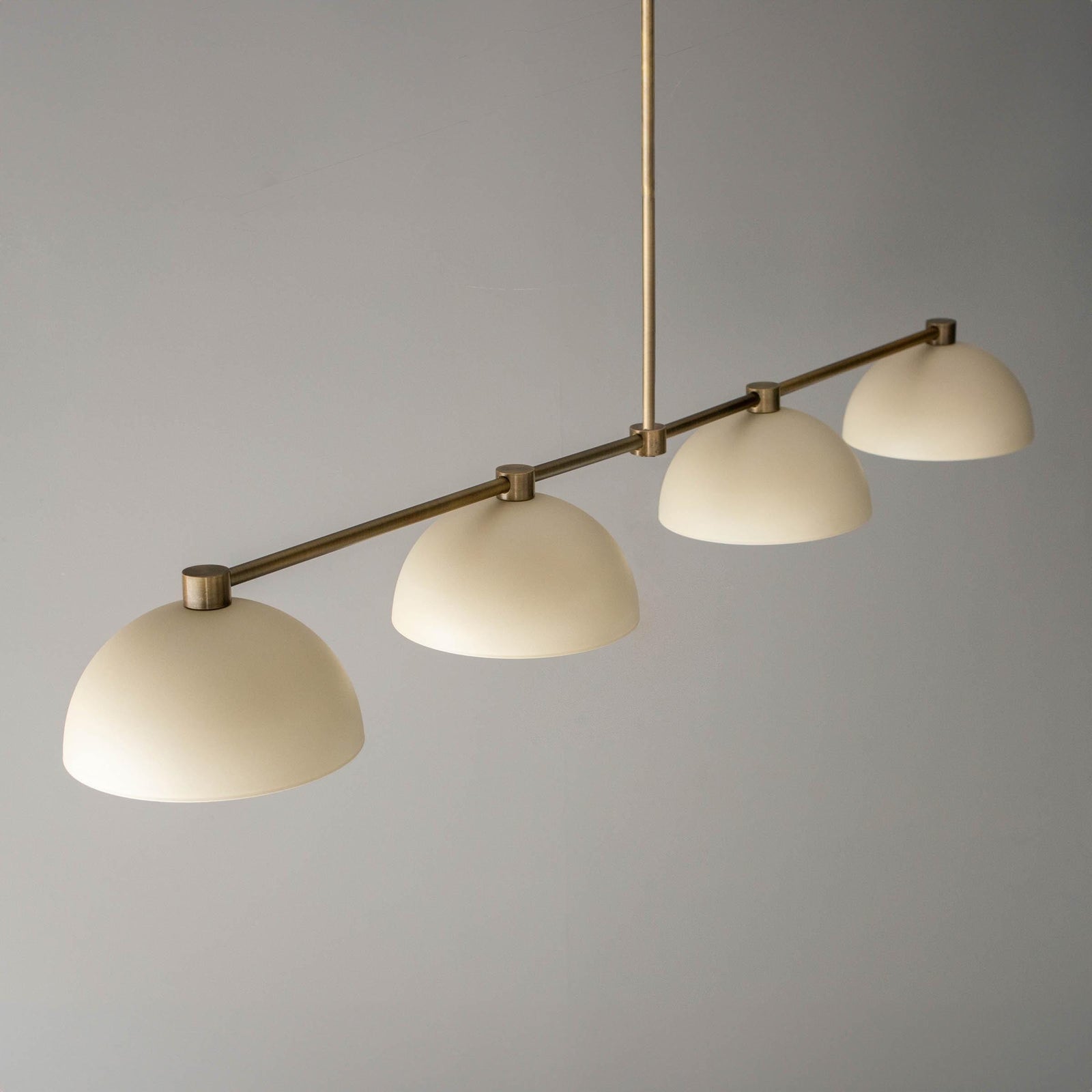 Antique brass chandelier with four cream dome-shaped shades suspended on a horizontal rod. - CHANDELIER MODEL NO. 4577