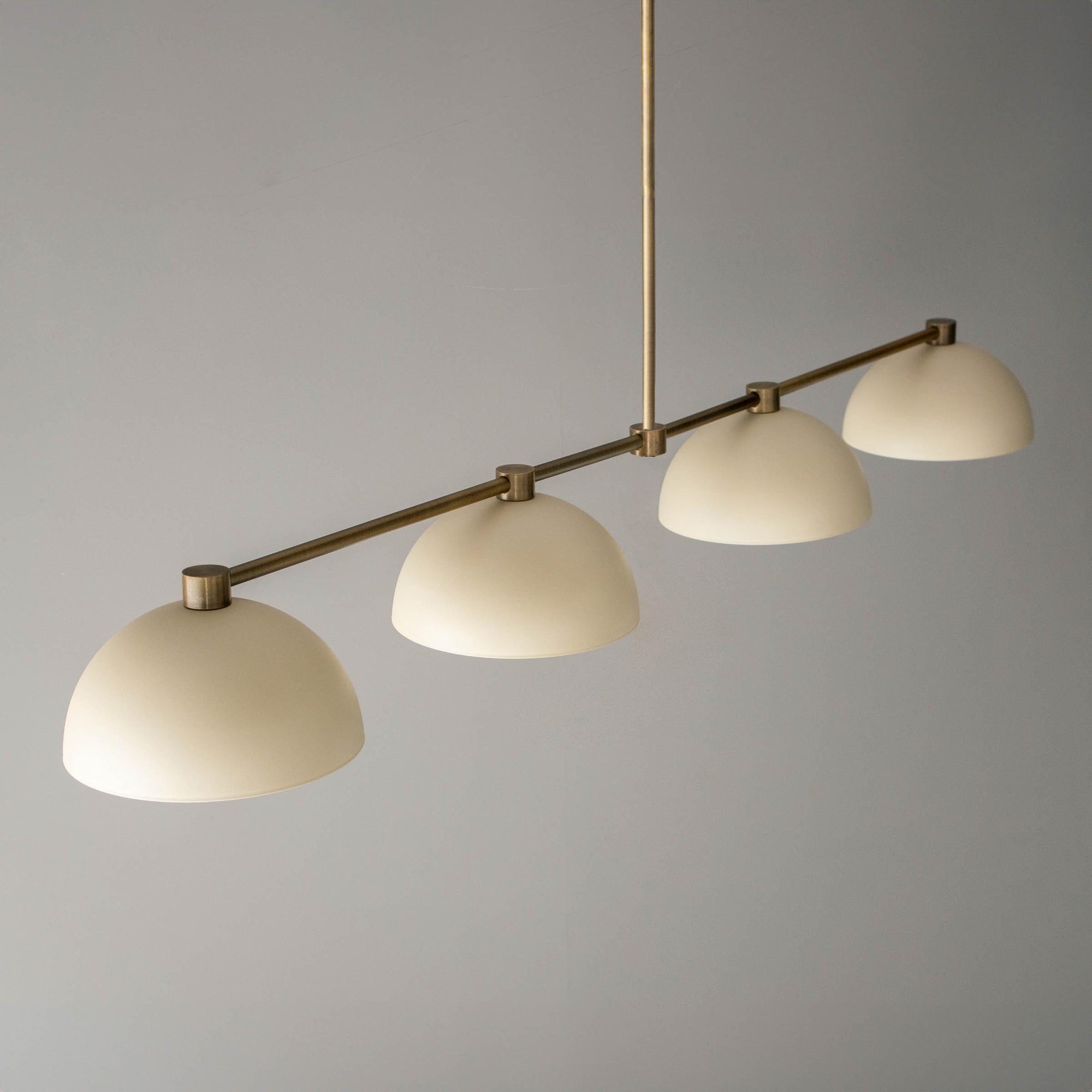 Antique brass chandelier with four cream dome-shaped shades suspended on a horizontal rod. - CHANDELIER MODEL NO. 4577