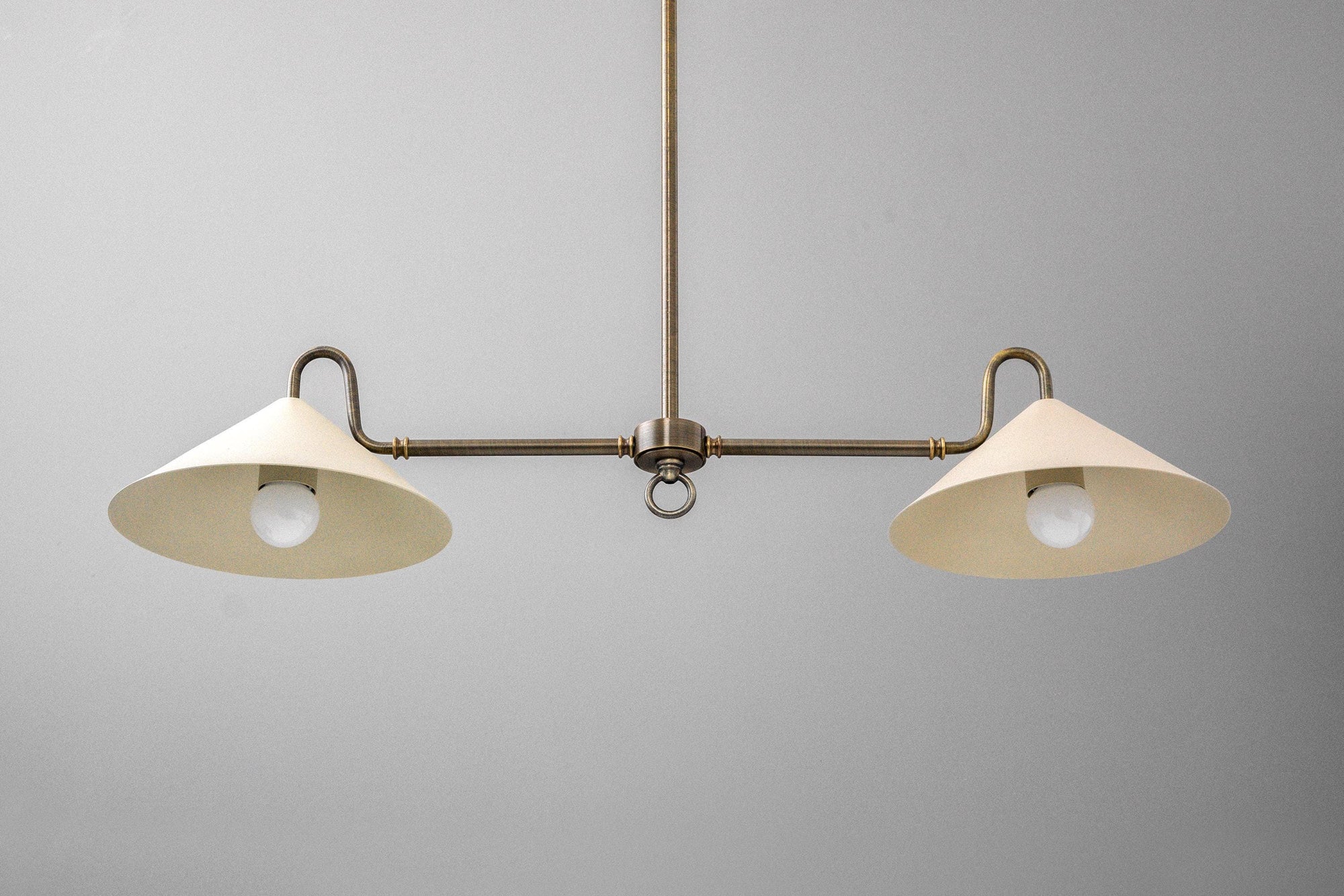 Antique brass linear chandelier with two cream fabric shades and exposed bulbs. - CHANDELIER MODEL NO. 7512