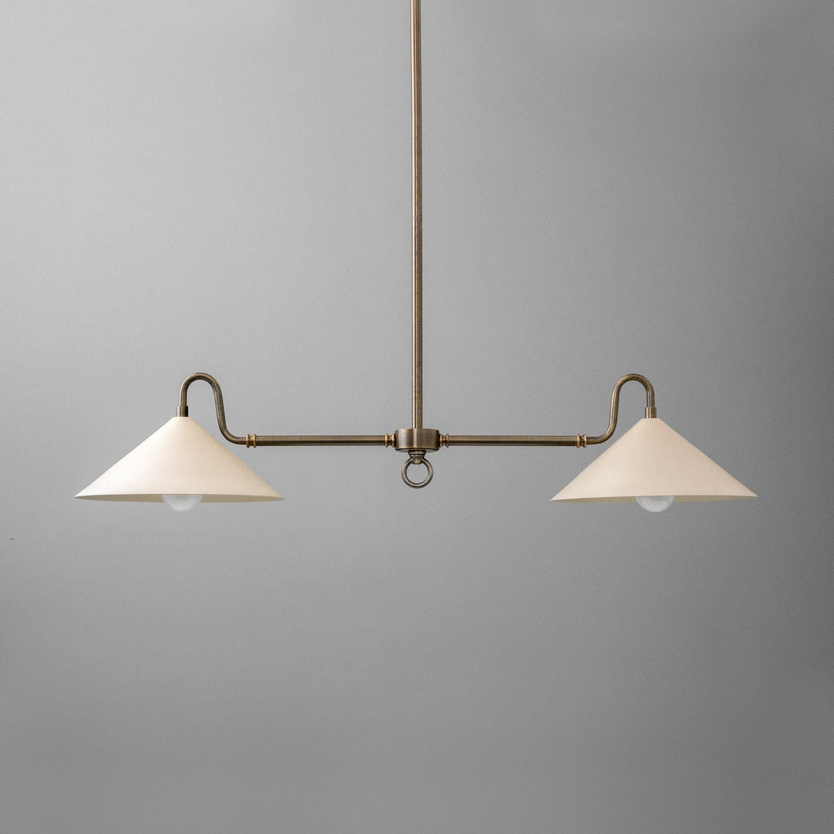 Antique brass linear chandelier with two cream cone-shaped shades on a central rod against gray background. - CHANDELIER MODEL NO. 7512
