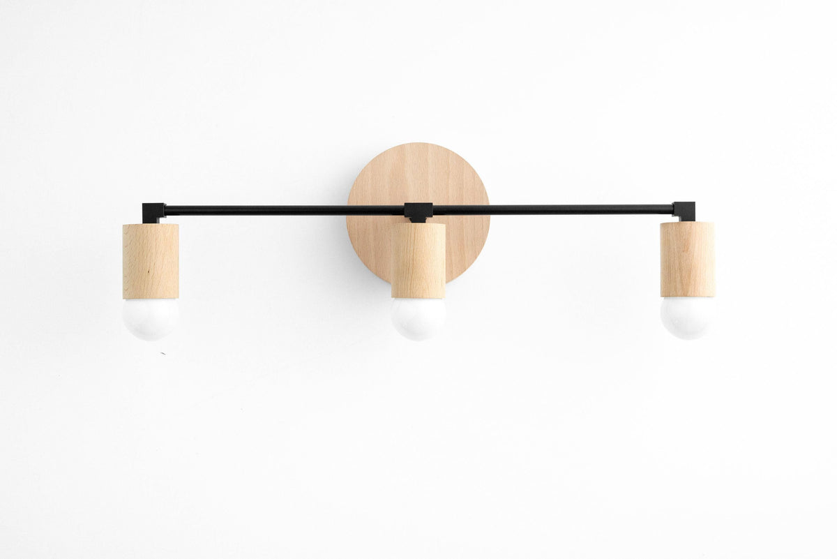 Three-bulb vanity light with black metal arms and beech wood accents on white background. - VANITY LIGHT MODEL NO. 4446