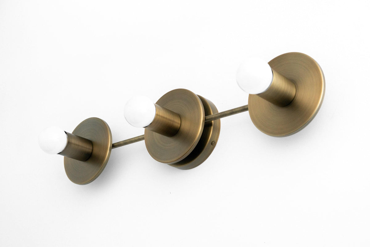Mid-century modern 3-bulb vanity light in antique brass with round wall mount and exposed white bulbs. - VANITY LIGHT MODEL NO. 5708