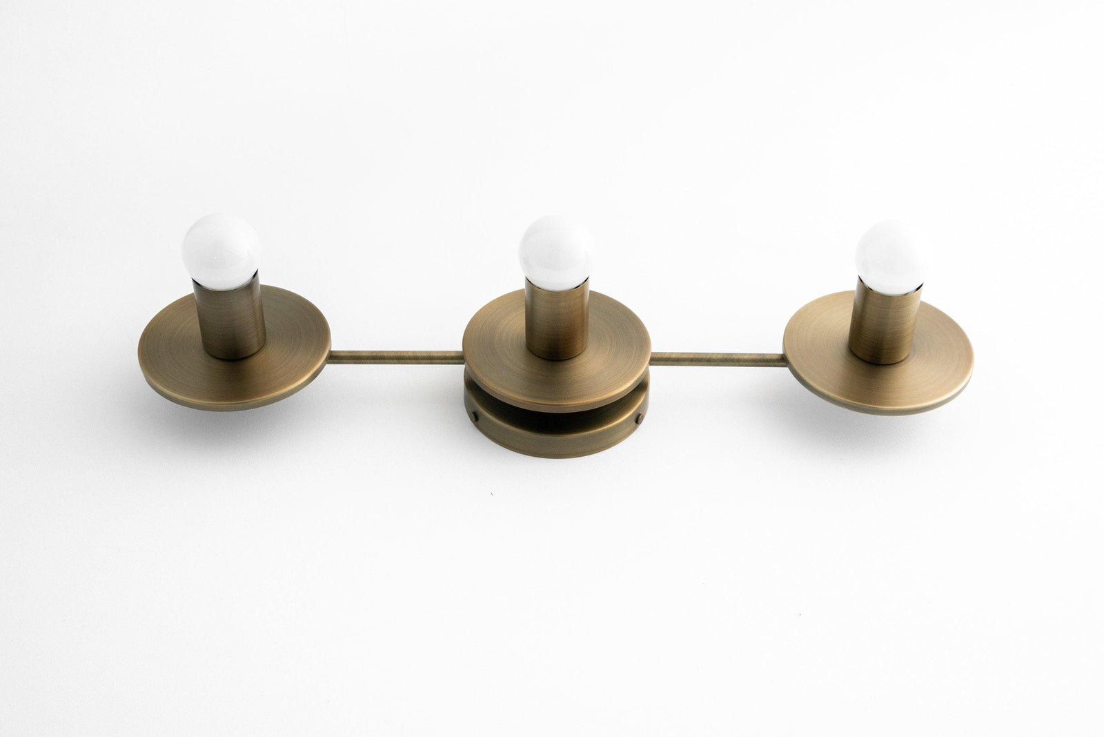 Three-bulb antique brass vanity light with round bases and exposed white bulbs. - VANITY LIGHT MODEL NO. 5708