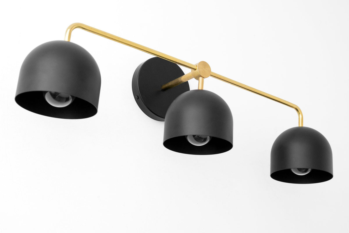Mid-century modern vanity light with three black dome shades and a sealed brass frame wall mount. - VANITY LIGHT MODEL NO. 7456