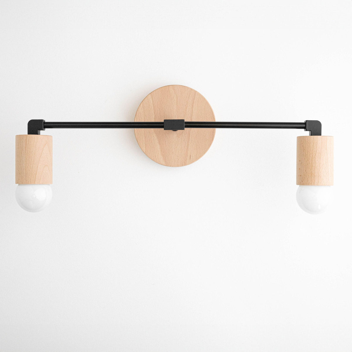 Two-light vanity light in Beech/Black/Beech with a round Beech wall plate, Beech sockets on a Black bar and bare globe bulbs. - VANITY LIGHT MODEL NO. 7357