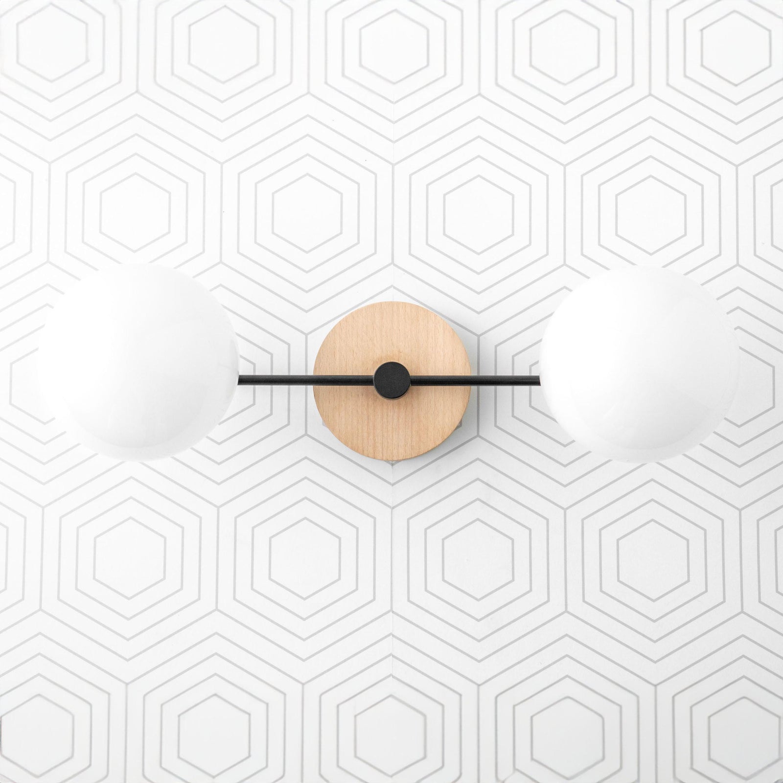 Two-globe vanity light with matte black metal arms and natural wood circular base on hexagonal tiled wall. - VANITY LIGHT MODEL NO. 9474