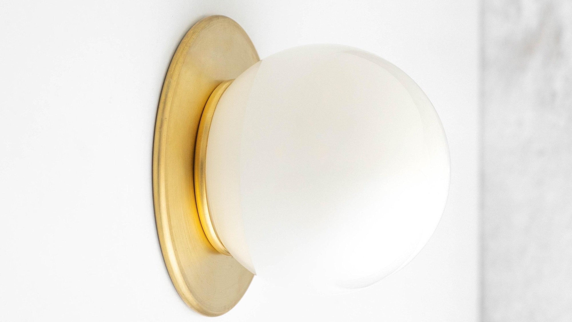Mid-century modern wall sconce with raw brass finish and frosted globe shade flush mounted to wall. - SCONCE MODEL NO. 9364