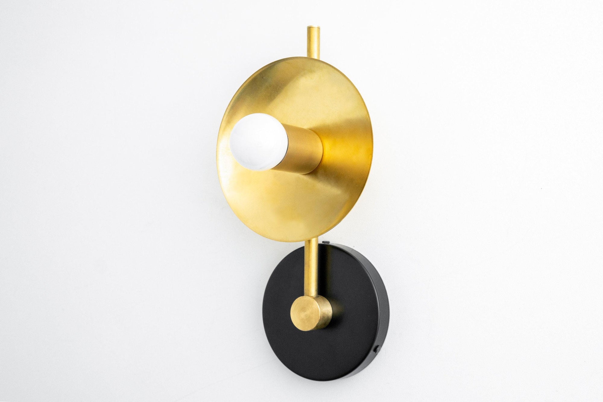 Black metal wall sconce with round brass reflector and exposed bulb. - SCONCE MODEL NO. 2693