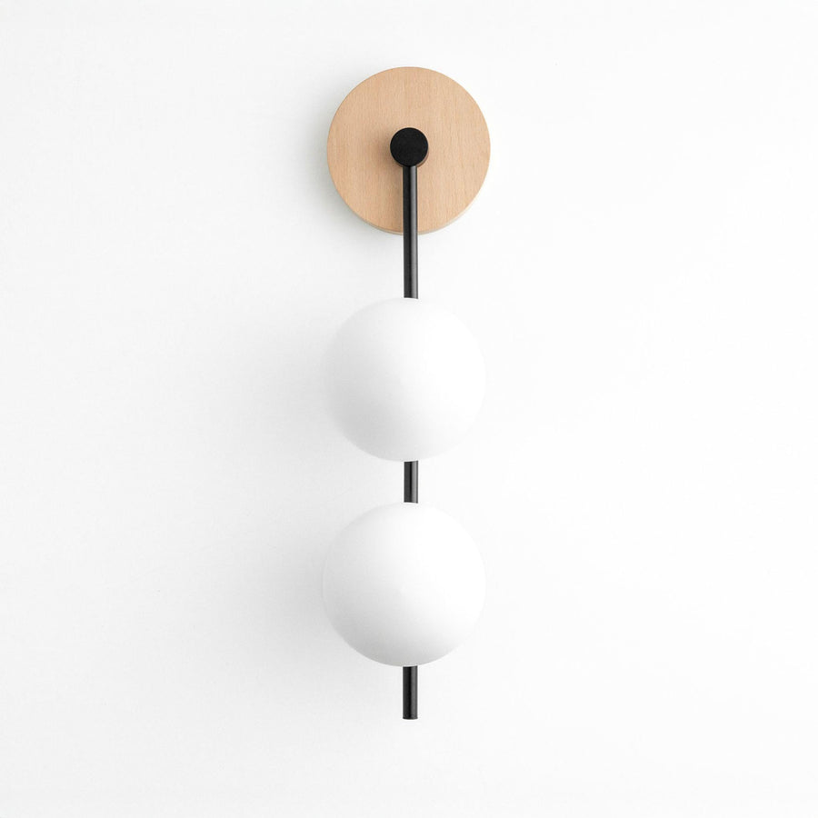 Minimalist wall sconce with natural wood round base and two white glass globes on black metal rods. - SCONCE MODEL NO. 0344