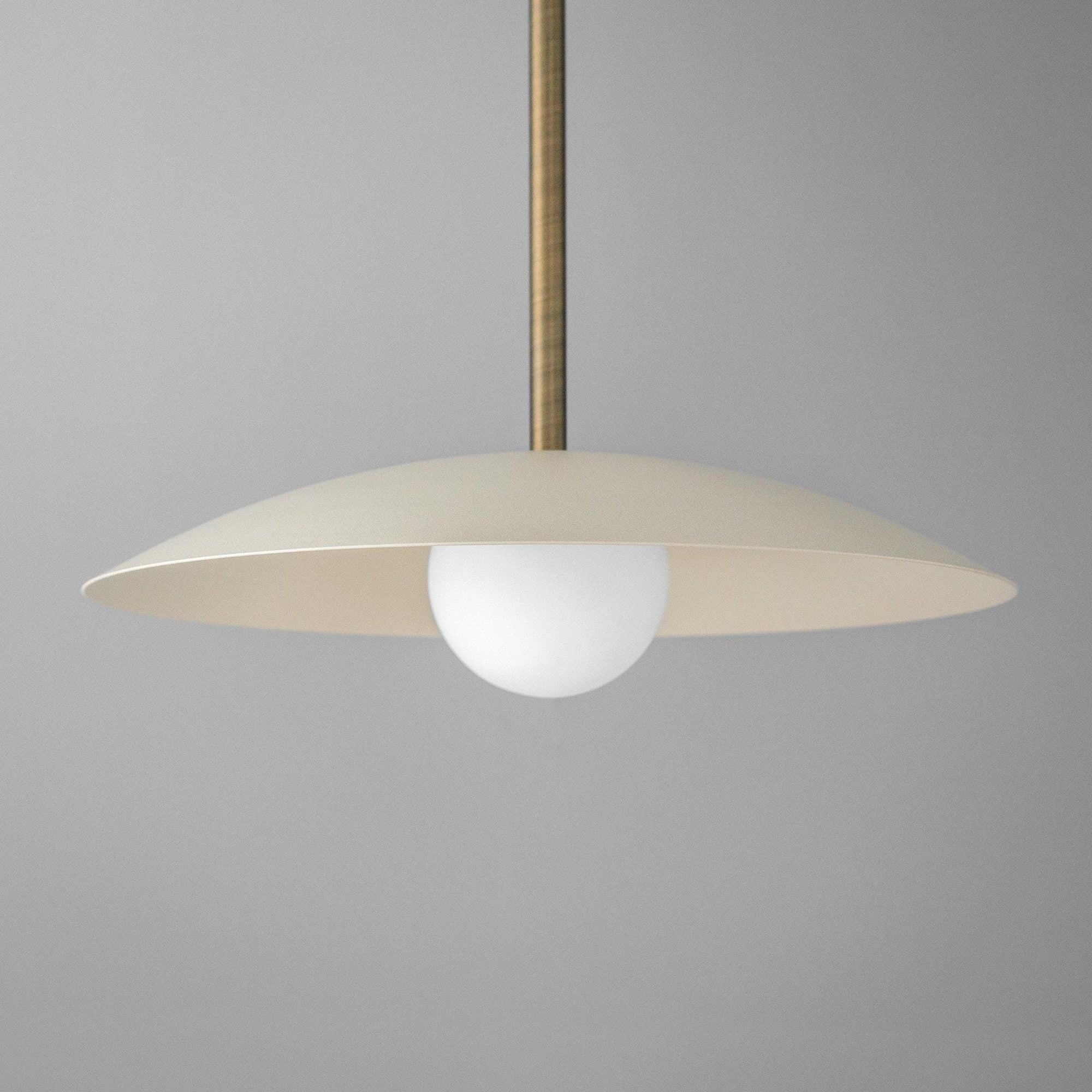 Mid-century modern pendant light with cream disc shade and round white globe bulb, antique brass rod. - PENDANT MODEL NO. 4085