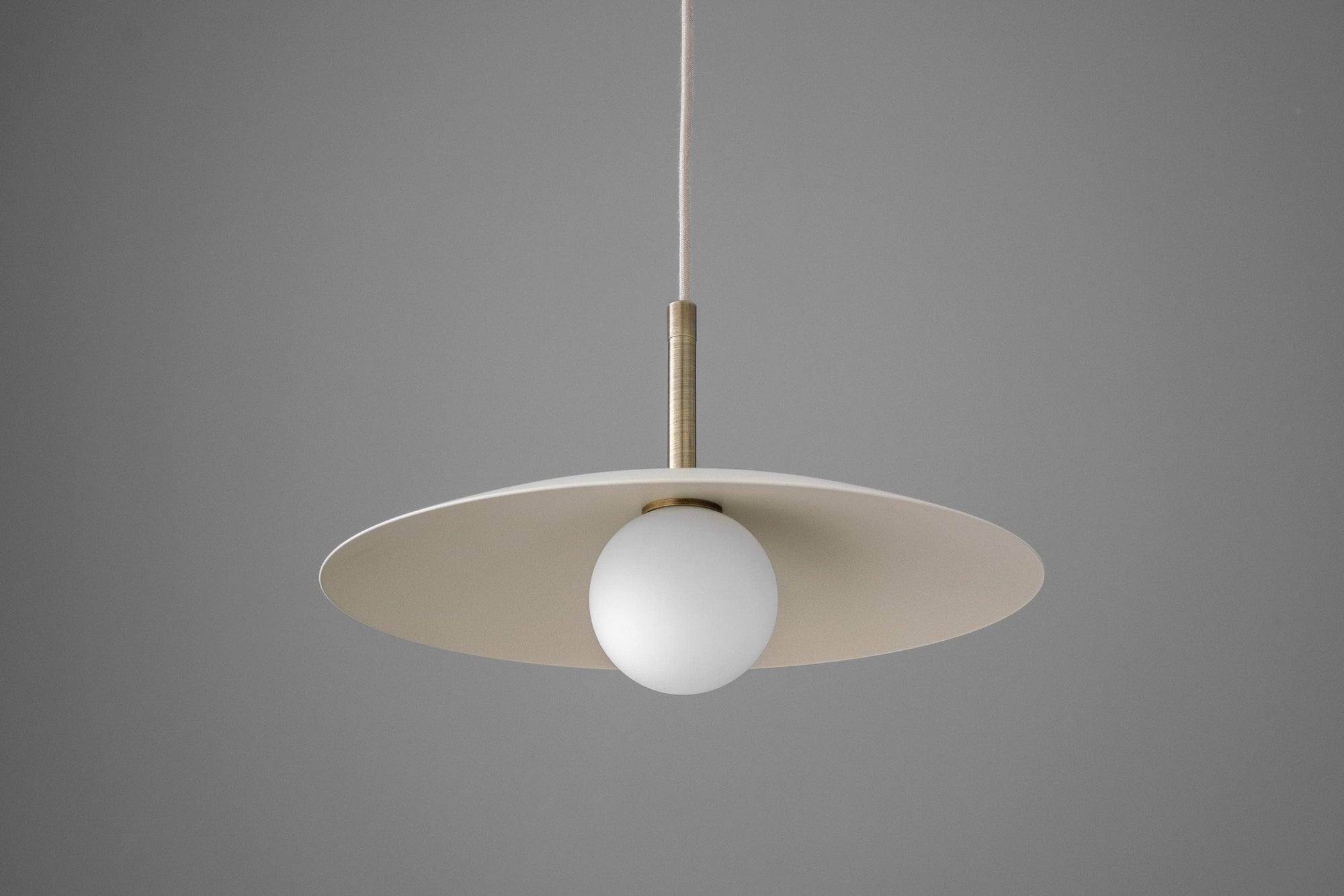 Minimalist pendant light with a flat, tan disc shade and a white globe bulb suspended by a thin cord. - PENDANT MODEL NO. 5693