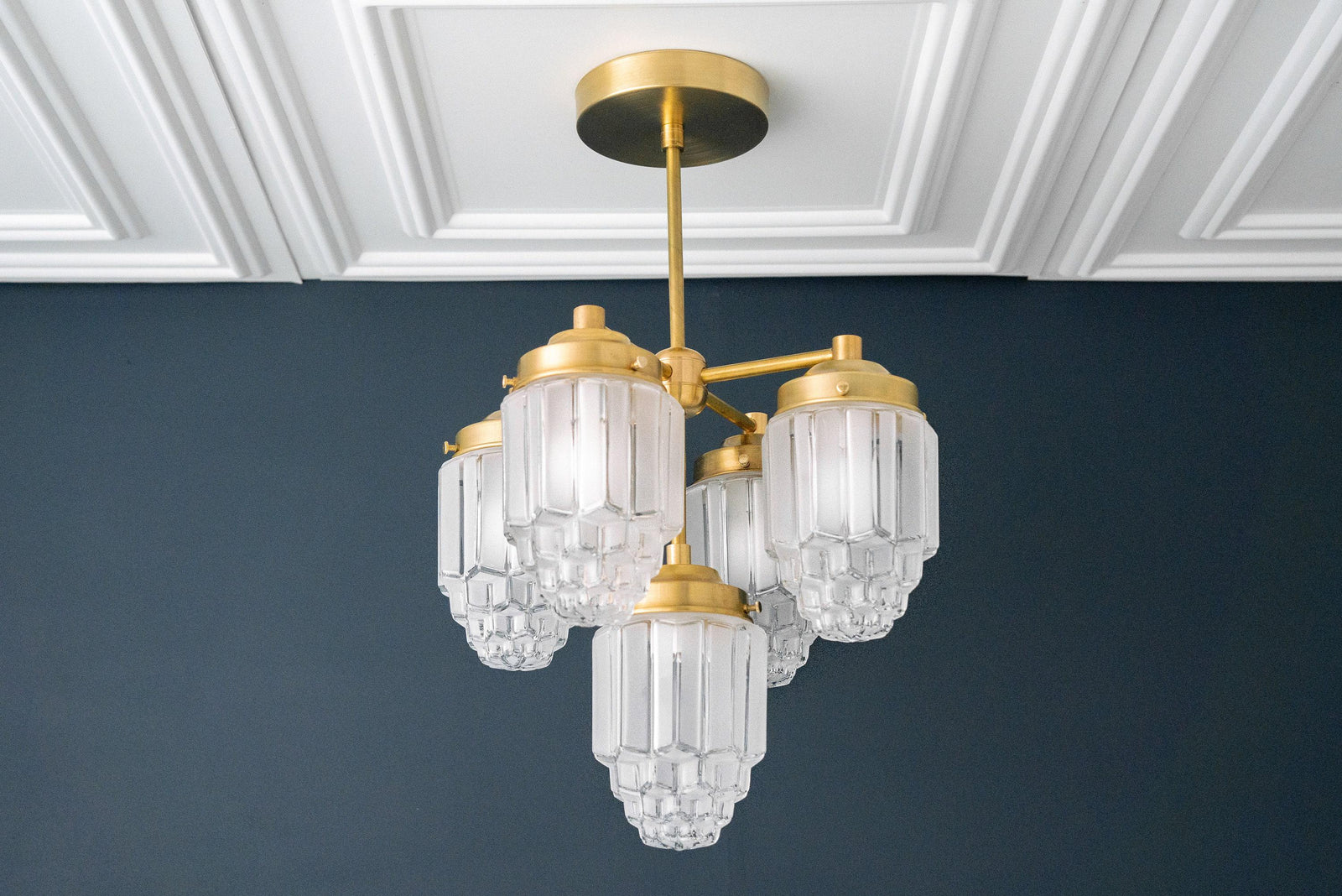 Art Deco chandelier in raw brass with three tiered glass globes hanging from a central rod. - CHANDELIER MODEL NO. 0777