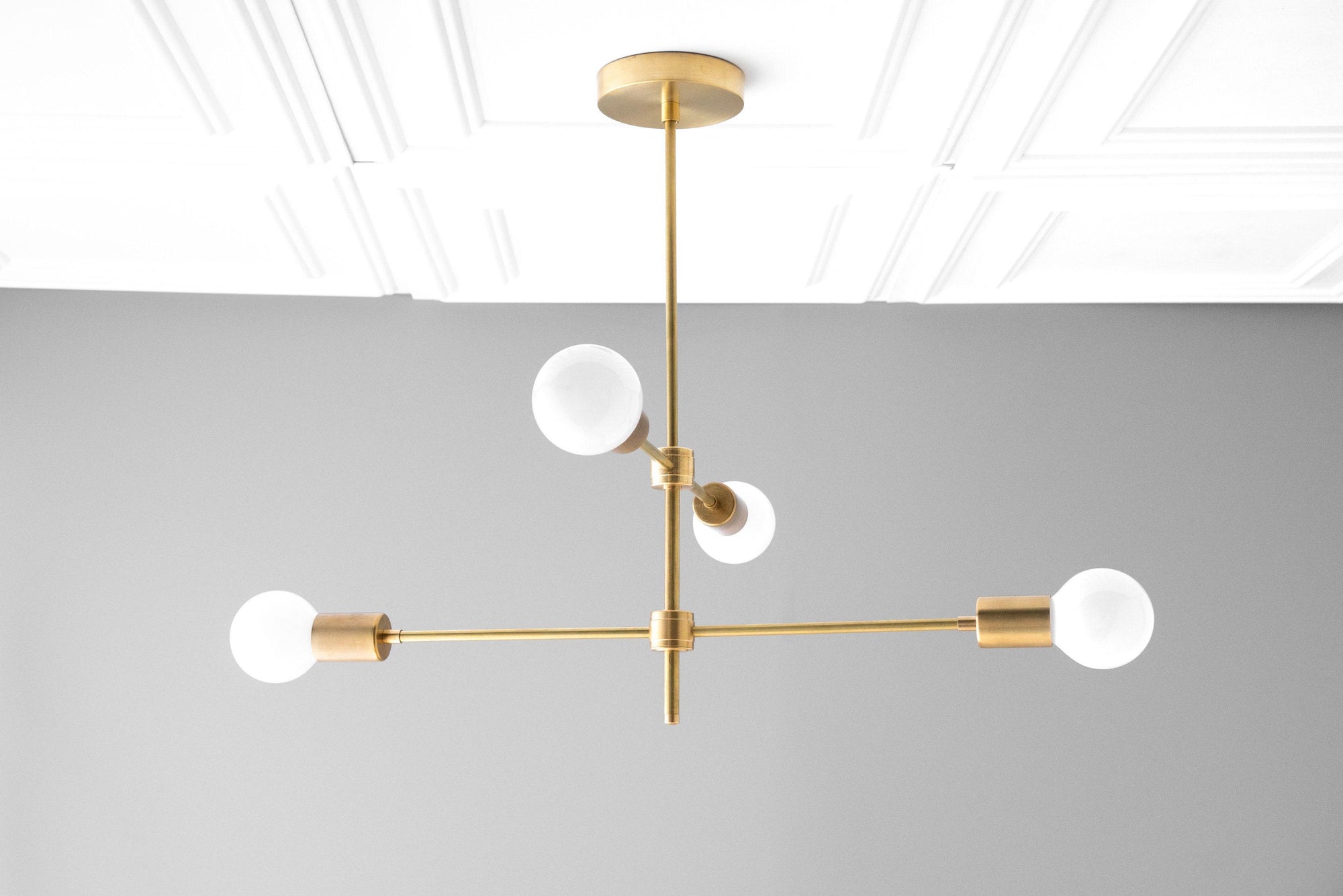 Art Deco chandelier with raw brass finish and four bare white globe bulbs on horizontal and vertical arms. - CHANDELIER MODEL NO. 5598