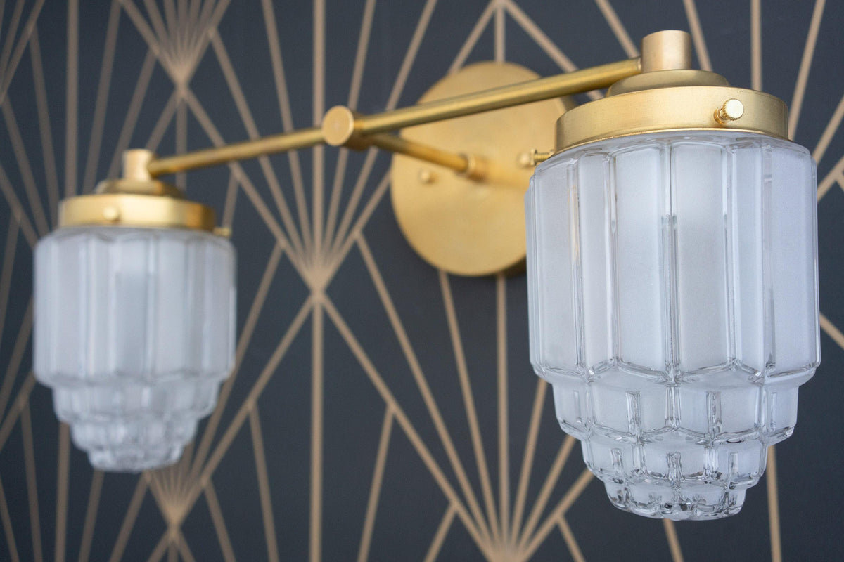Industrial style 2-bulb vanity light in raw brass with fluted glass globe shades on black patterned wall. - VANITY LIGHT MODEL NO. 9777