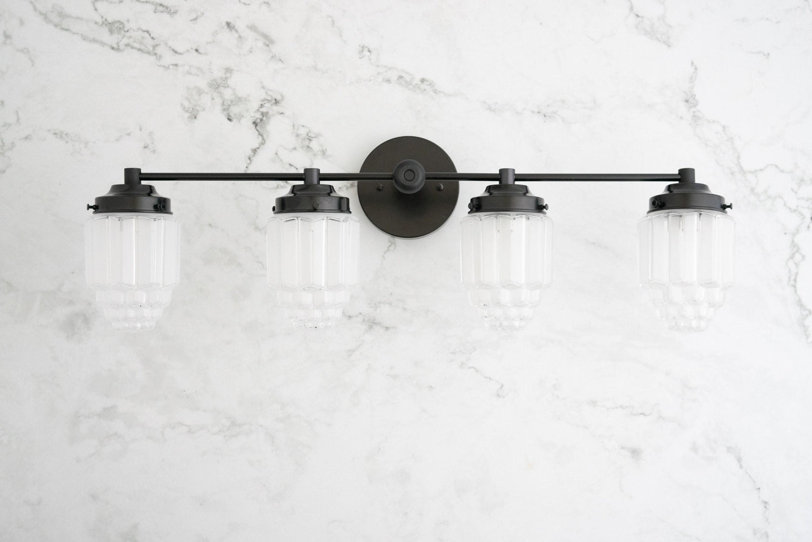 Four-bulb black metal vanity light with ribbed glass globe shades mounted on marble wall. - VANITY LIGHT MODEL NO. 1082
