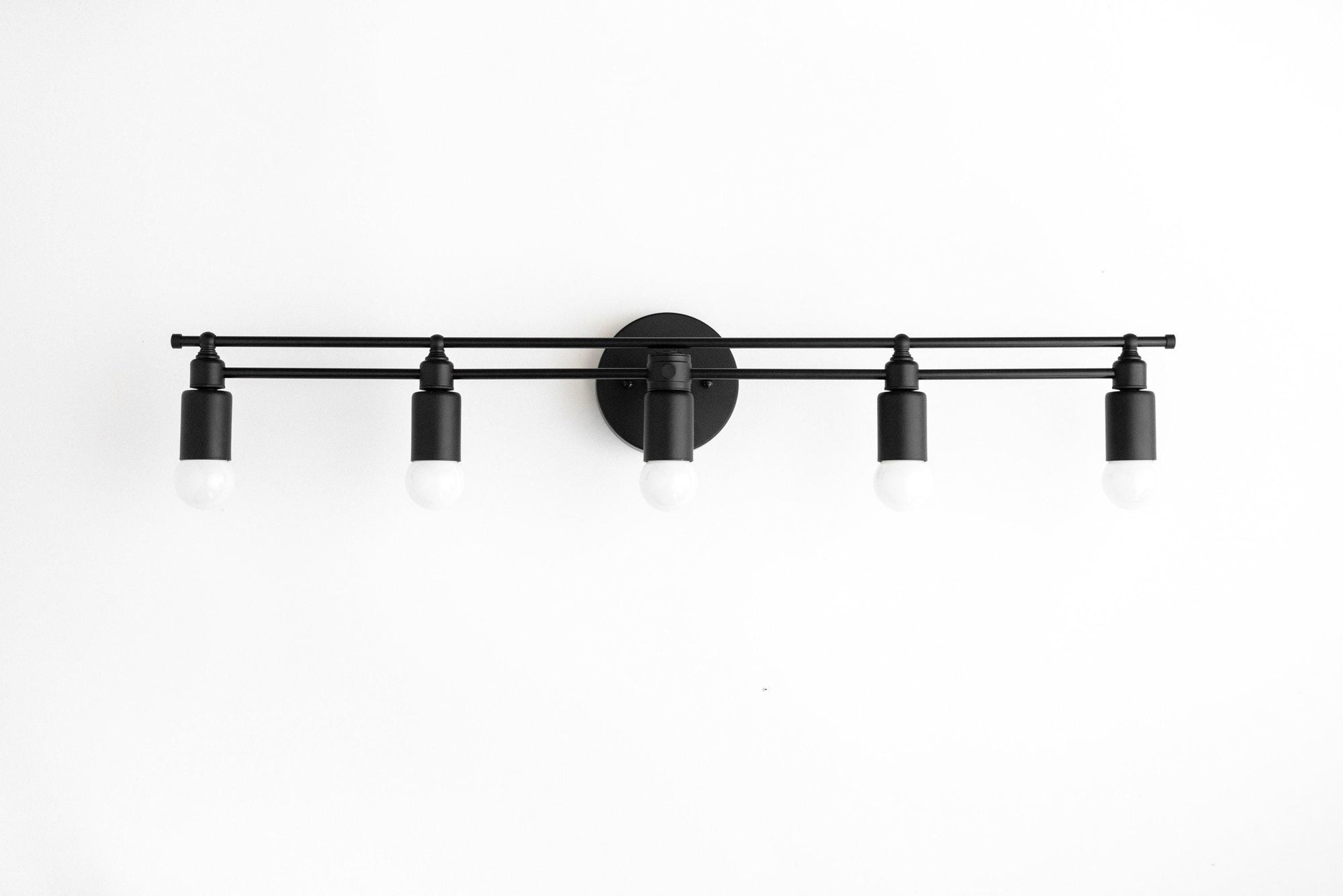 Black metal vanity light with five bare bulb sockets and round wall mount. - VANITY LIGHT MODEL NO. 3933