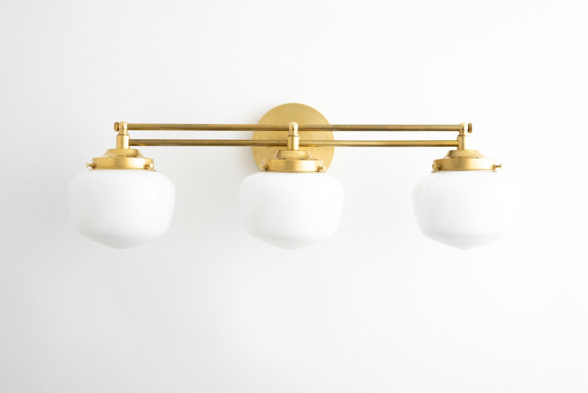 Three-bulb vanity light with white globe shades and polished brass finish, Art Deco style. - VANITY LIGHT MODEL NO. 4352