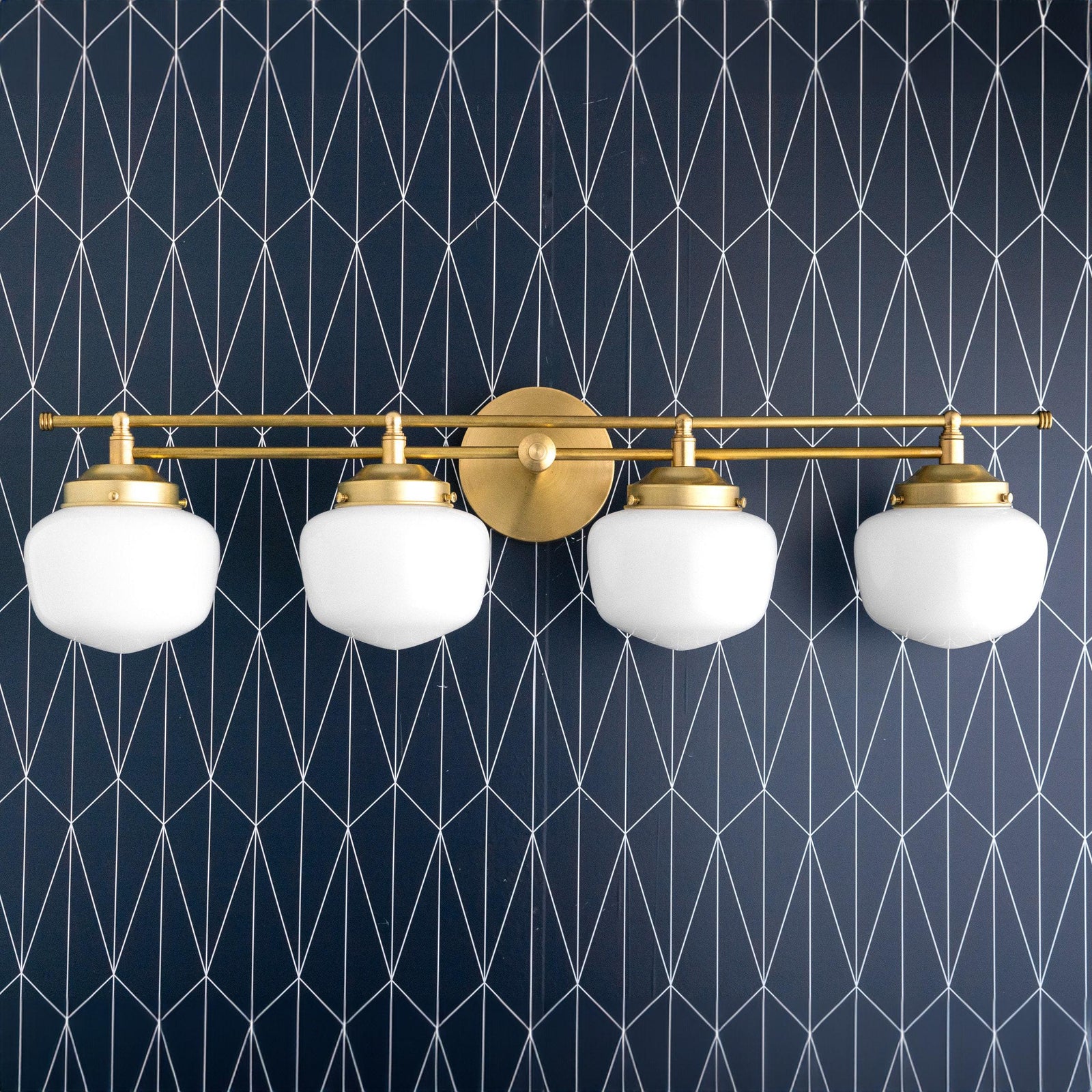 Four-bulb vanity light with raw brass finish and white globe shades against dark geometric wallpaper. - VANITY LIGHT MODEL NO. 9054