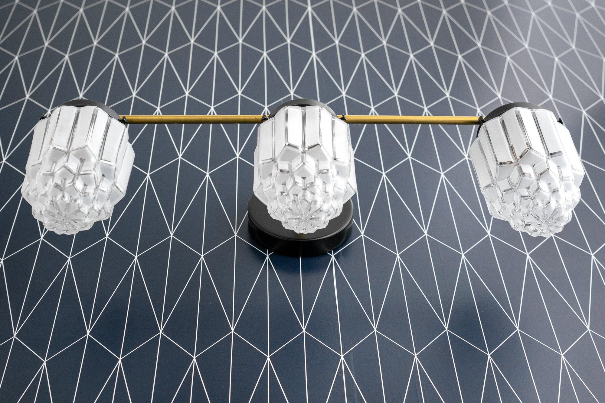 3-bulb vanity light with polished nickel finish and geometric frosted glass globes on black patterned wall. - VANITY LIGHT MODEL NO. 3918